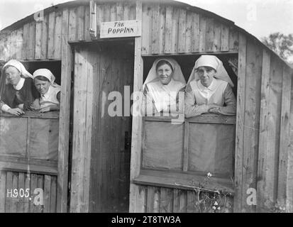 Le infermiere guardano fuori dalle finestre del New Zealand Stationary Hospital, Wisques, Francia, durante la prima guerra mondiale, quattro sorelle infermieristiche non identificate guardano fuori dalle finestre di un edificio di un ospedale stazionario neozelandese a Wisques, Francia, durante la prima guerra mondiale. Sopra la porta c'è un cartello con la scritta "The Popp Inn". Fotografia scattata il 16 agosto 1918 Foto Stock