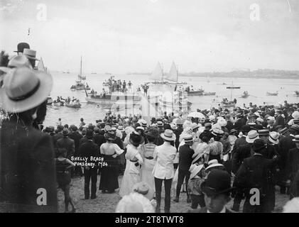 Capodanno a Shelly Beach, Auckland, nuova Zelanda, veduta della folla che si trova vicino al bordo dell'acqua e guarda l'attività a bordo di yacht e barche vicino alla riva. Preso da dietro la folla e affacciato sul mare. Forse l'ocassione era la regata di Capodanno. Presa, il 1 gennaio 1914 Foto Stock