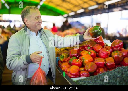 Uomo che acquista peperoni in gregrocery Foto Stock
