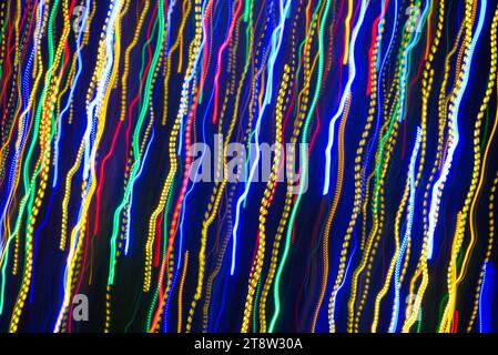 I motivi di luce sfocati e multicolore presentano striature su uno sfondo scuro creando forme astratte Foto Stock