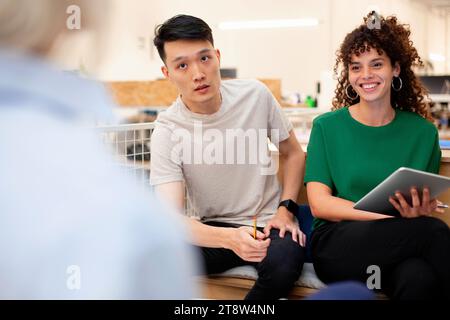 Colleghi che utilizzano un tablet digitale mentre parlano con un collega in ufficio Foto Stock