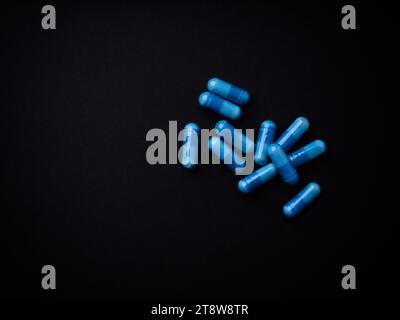 Capsule di aminoacidi su sfondo di carta scura. Messa a fuoco morbida. Vista dall'alto. Primo piano. Copia spazio. Foto Stock