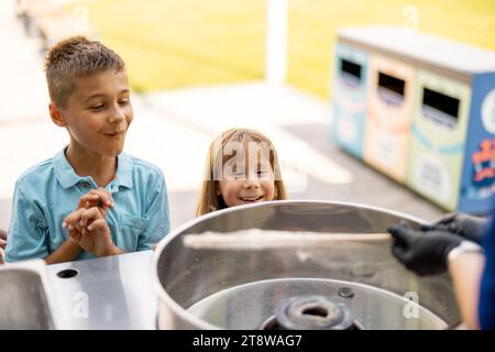 Bambina e ragazzo in attesa di un dolce zucchero di cotone al parco divertimenti Foto Stock