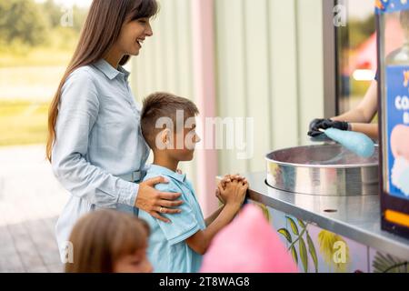 Mamma con bambini in attesa di un dolce zucchero di cotone al parco divertimenti Foto Stock