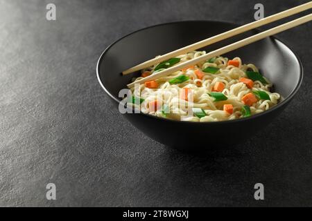 Spaghetti istantanei con verdure nel recipiente, su sfondo scuro, messa a fuoco selettiva. Foto Stock