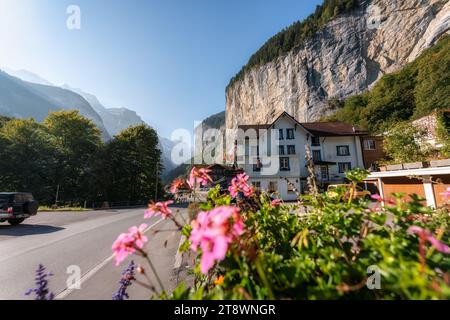 Splendido villaggio rustico con fiori in fiore, hotel in legno e cascata che scorre dalla montagna di Lauterbrunnen, Svizzera Foto Stock