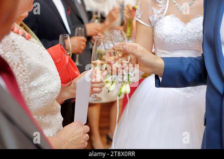 Bicchieri con champagne nelle mani della Sposa e del Groom alzati per un brindisi Foto Stock
