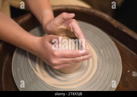 Potter Girl lavora sulla ruota di potter, realizzando pentole in ceramica con l'argilla in un laboratorio di ceramica. Arte e hobby Foto Stock