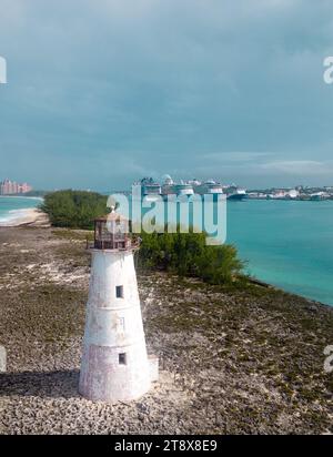 Questa splendida immagine presenta un maestoso faro bianco circondato da un tranquillo mare turchese e da una spiaggia di sabbia incontaminata Foto Stock