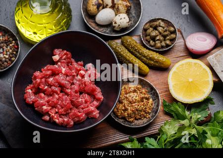 Cottura di una saporita tartare di manzo con cetriolini sottaceto e pane tostato. Spianatura piatta Foto Stock