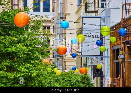 Albero verde collegato a luci a corda e lanterne colorate con lati degli edifici a San Francisco, CA Foto Stock