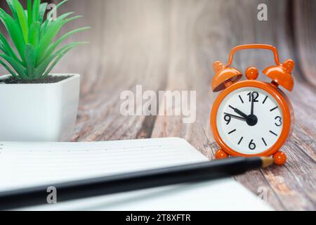 Blocco note con impianto in vaso e sveglia impostata alle 10.00. Foto Stock