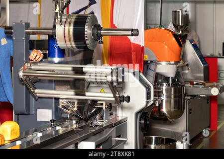Il pane cotto su un nastro trasportatore si sposta per essere sigillato in una macchina di imballaggio sulla linea di produzione di una fabbrica di prodotti da forno. Foto Stock