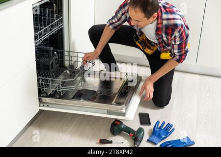 Vista dell'uomo in generale Riparazione lavastoviglie in cucina Foto Stock