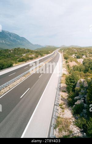 Una lunga e tortuosa autostrada che si estende attraverso un paesaggio montuoso. Il terreno circostante è aspro, con colline e montagne ricoperte di vegetazione. Foto Stock