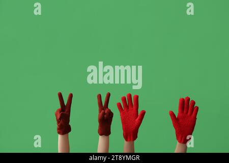 Donne con eleganti guanti caldi che mostrano il gesto della vittoria su sfondo colorato Foto Stock