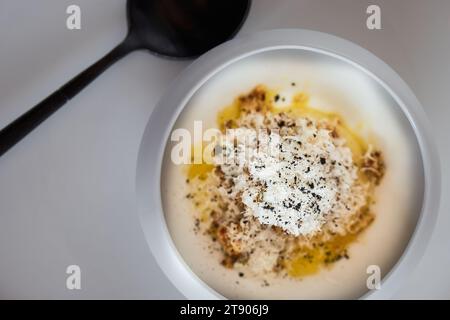 Piatto gastronomico uova e parmigiano in piccola ciotola bianca con cucchiaio, vista dall'alto Foto Stock