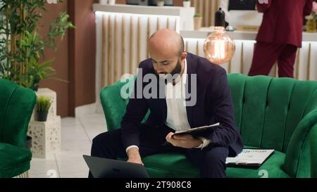 Imprenditore che lavora su idee di progetto mentre aspetta nell'area lounge, in viaggio d'affari. Manager inviato a negoziare con i collaboratori per garantire la partnership per la crescita dell'azienda sulla scena globale. Foto Stock