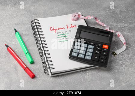 Indice glicemico. Notebook con informazioni, pennarelli, calcolatrice e metro a nastro su un tavolo grigio chiaro Foto Stock