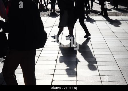 immagine delle sagome retroilluminate dei pedoni che camminano in una zona pedonale Foto Stock