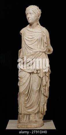Roman Matron, 60–70, 50 1/2 x 13 x 10 1/2 poll. (128,27 x 33,02 x 26,67 cm), marmo, romano, i secolo, una volta identificato come Agrippina il giovane, madre dell'imperatore Nerone, si pensa che questa statua rappresenti una matrona romana non identificata. L'acconciatura, una caratteristica spesso usata per datare antichi ritratti femminili romani, corrisponde a una moda durante il regno di Nerone (54-68 d.C.) la rappresentazione cruda e realistica del volto osseo e foderato della donna contrasta con le pieghe dell'abbigliamento fluide e profondamente scolpite, caratteristiche della scultura tardo greca (ellenistica). Foto Stock