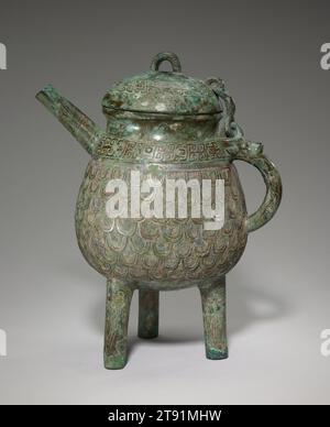 Vaso del vino, XI-X secolo a.C., 11 1/2 x 9 7/16 x 6 5/8 pollici, 7,1 libbre (29,21 x 23,97 x 16,83 cm, 3,2 kg), Bronzo, Cina, XI-X secolo a.C., il contenitore di vino He è un vecchio tipo di vaso che è emerso già nel periodo Erlitou, risalente al XVII secolo a.C. Durante la tarda dinastia Shang (circa 1300–1046 a.C.), la sua forma si è evoluta: Il suo corpo rigonfiato, con collo stretto e beccuccio, era supportato da tre gambe cilindriche, come visto in questo esempio. Il vaso reca un'iscrizione che identifica che è stato lanciato da 'Shi' in onore di suo padre, 'Gui'. Foto Stock