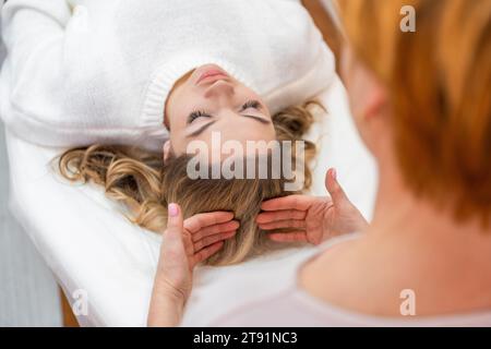 Donna guaritrice che esegue una terapia con barre di accesso leggermente toccate sulla testa di una giovane donna, stimolando pensieri ed emozioni di cambiamento positivo. Alternativa Foto Stock