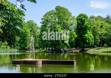 Paesaggio vivido nel parco Nicolae Romaescu da Craiova nella contea di Dolj, Romania, con lago, lillie d'acqua e grandi tres verdi in una splendida sprina soleggiata Foto Stock