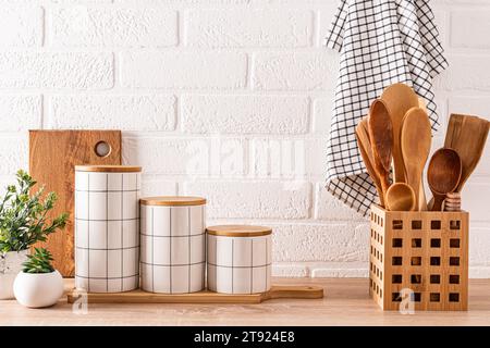 Splendido sfondo da cucina con set di taglieri, cucchiai in legno, eleganti vasetti in ceramica. Vista frontale. Cucina ecocompatibile. Foto Stock