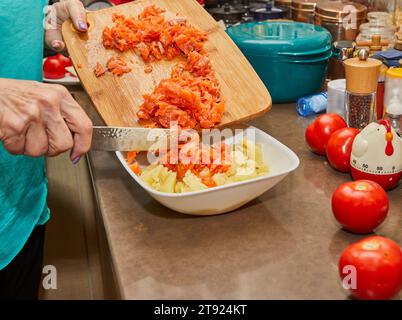 Lo chef mette i pomodori tagliati finemente in purè di patate. Foto Stock