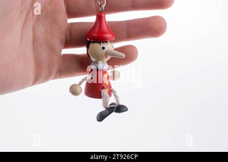 Pinocchio in legno bambola con il suo naso lungo su sfondo bianco Foto Stock