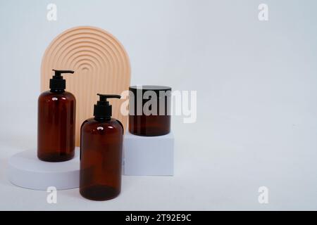 Composizione con forme geometriche.cura del corpo. due biberon con dispenser e vaso di panna, su sfondo grigio chiaro. Concetto pubblicitario Foto Stock