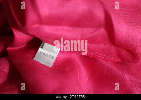 Etichetta di abbigliamento in diverse lingue su indumenti rosa, primo piano Foto Stock