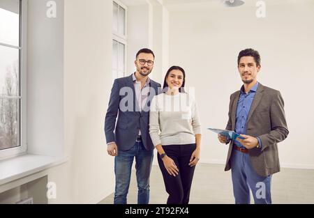 Giovane coppia felice alla ricerca di una nuova casa con realtor. Concetto di mercato immobiliare. Foto Stock