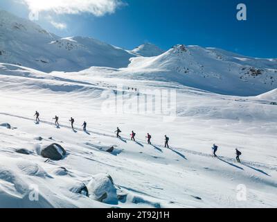 Veduta aerea di un gruppo di trekking che sale in fila le alpi francesi lasciando piste innevate con la valle ricoperta di neve di Saint-Martin-de-Belleville, Savoia Foto Stock