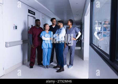 Felici diversi medici maschi e femmine che parlano nel corridoio dell'ospedale Foto Stock