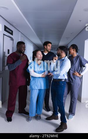 Felici diversi medici maschi e femmine che parlano nel corridoio dell'ospedale Foto Stock