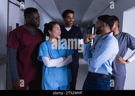 Felici diversi medici maschi e femmine che parlano nel corridoio dell'ospedale Foto Stock