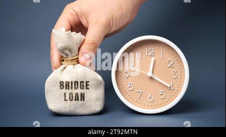 Money bag Bridge Loan and clock. Prestito a breve termine utilizzato fino a quando una persona o una società non ottiene finanziamenti permanenti. Concetto di business e finanza Foto Stock