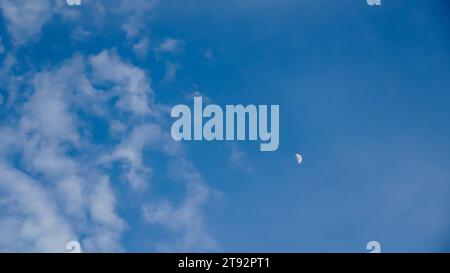 Mezza luna nel cielo di giorno con nuvole vaghe ambiente ambiente sfondo. Nuvole bianche e cielo blu. Nuvole con sfondo. Foto Stock