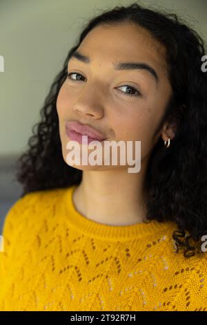 Ritratto ravvicinato della donna birazziale in maglione giallo a casa Foto Stock