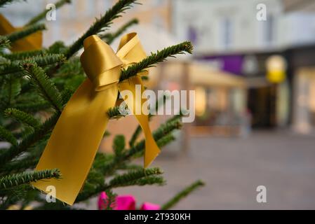 Immergetevi nello spirito natalizio con una vista su un albero di Natale adornato da un radioso nastro d'oro, sullo sfondo di marrone chiaro e W. Foto Stock