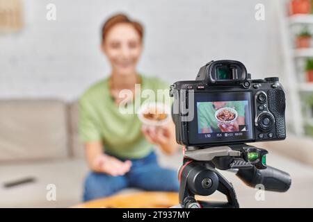 concentrati sulla fotocamera digitale vicino a una donna vegetariana con ciotola di noci, video blog sulle diete a base di piante Foto Stock