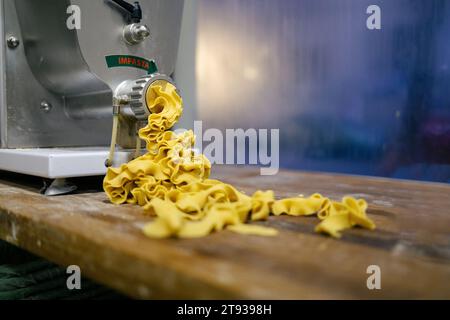 Pasta appena fatta che esce dalla macchina in una panetteria Foto Stock