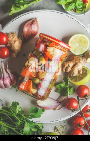 Vista dall'alto del recipiente di conservazione con varie verdure sott'aceto sul piatto con ingredienti Foto Stock