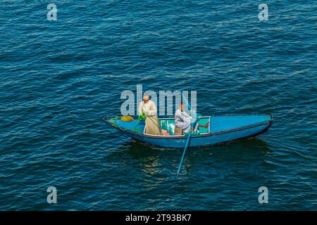 I venditori di tessuti sulle loro barche si avvicinano a una nave da crociera in attesa di entrare nella chiusa di Esna. I venditori sperano di vendere beni ai turisti. Esna, Egitto – 20 ottobre Foto Stock