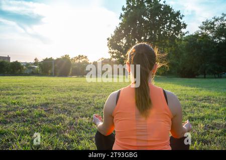 Vista posteriore di Young Woman che fa yoga in Park con una postura serena e calma Foto Stock
