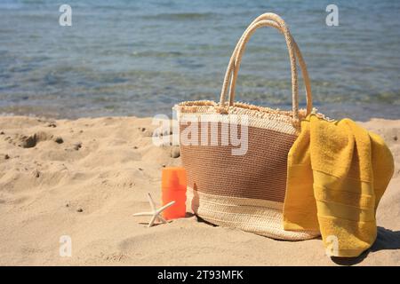 Crema solare, stelle marine, borsa e asciugamano sulla spiaggia, spazio per il testo. Protezione solare Foto Stock