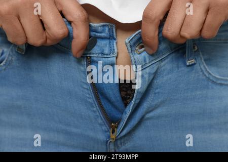 Donna che cerca di indossare jeans stretti, primo piano Foto Stock