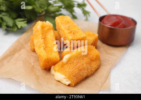 Gustosi bastoncini di mozzarella fritti serviti con ketchup su tavolo bianco, primo piano Foto Stock